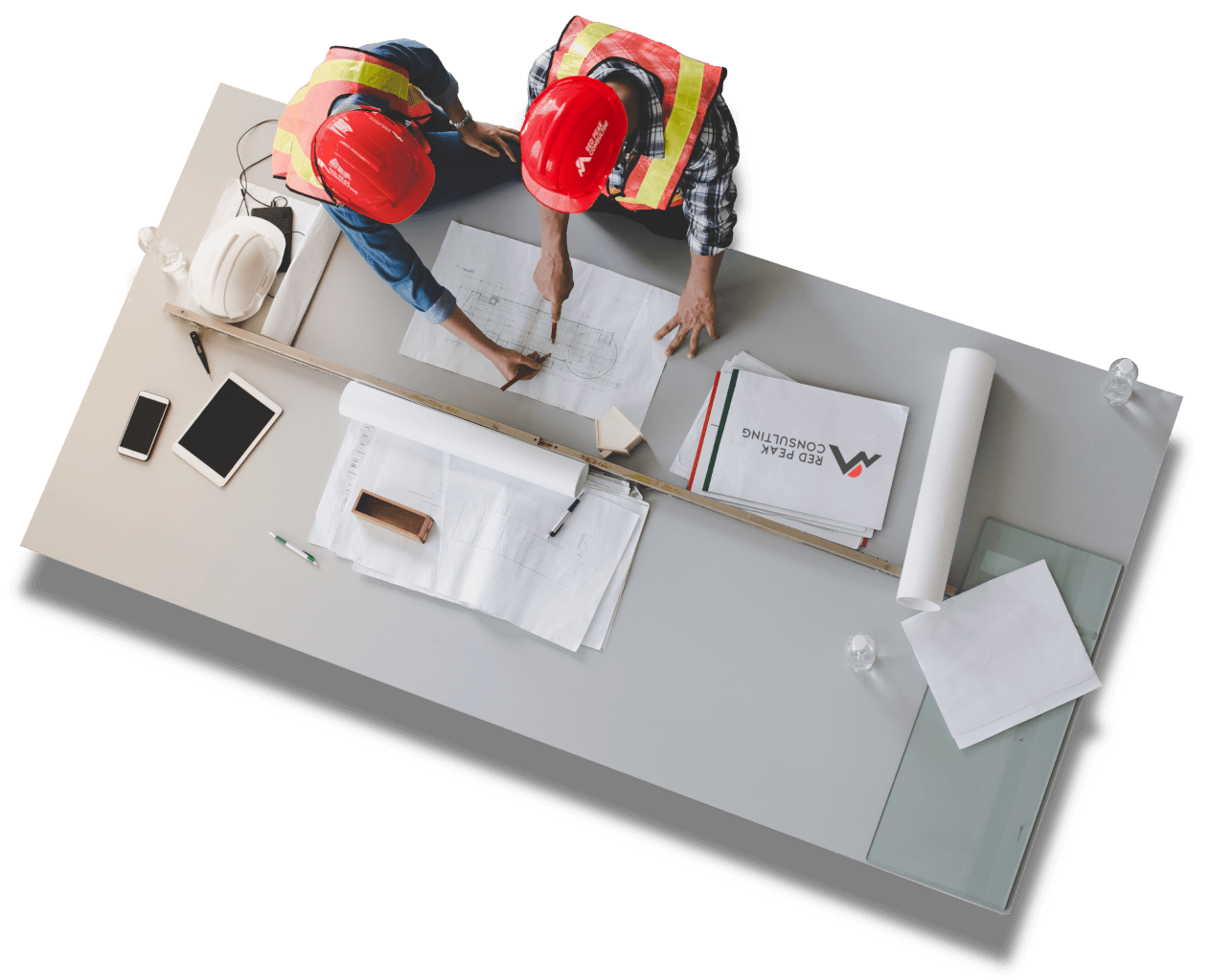 Top-down view of two workers in hard hats reviewing plans on a table.