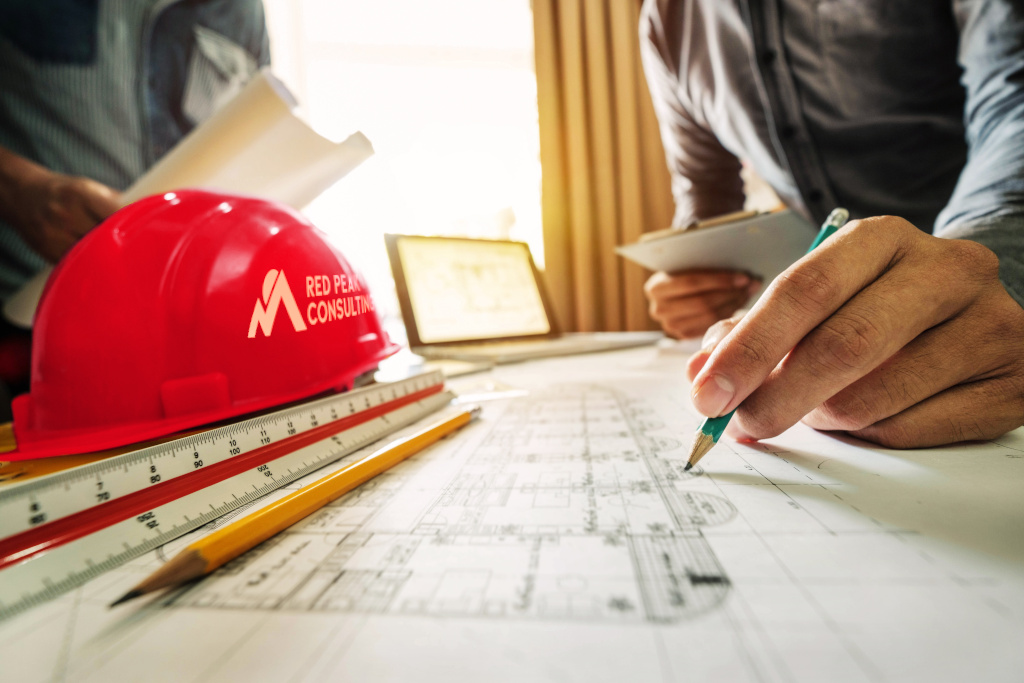 Hard hat, project plans, and drawing materials on a table, representing advisory and strategy services.
